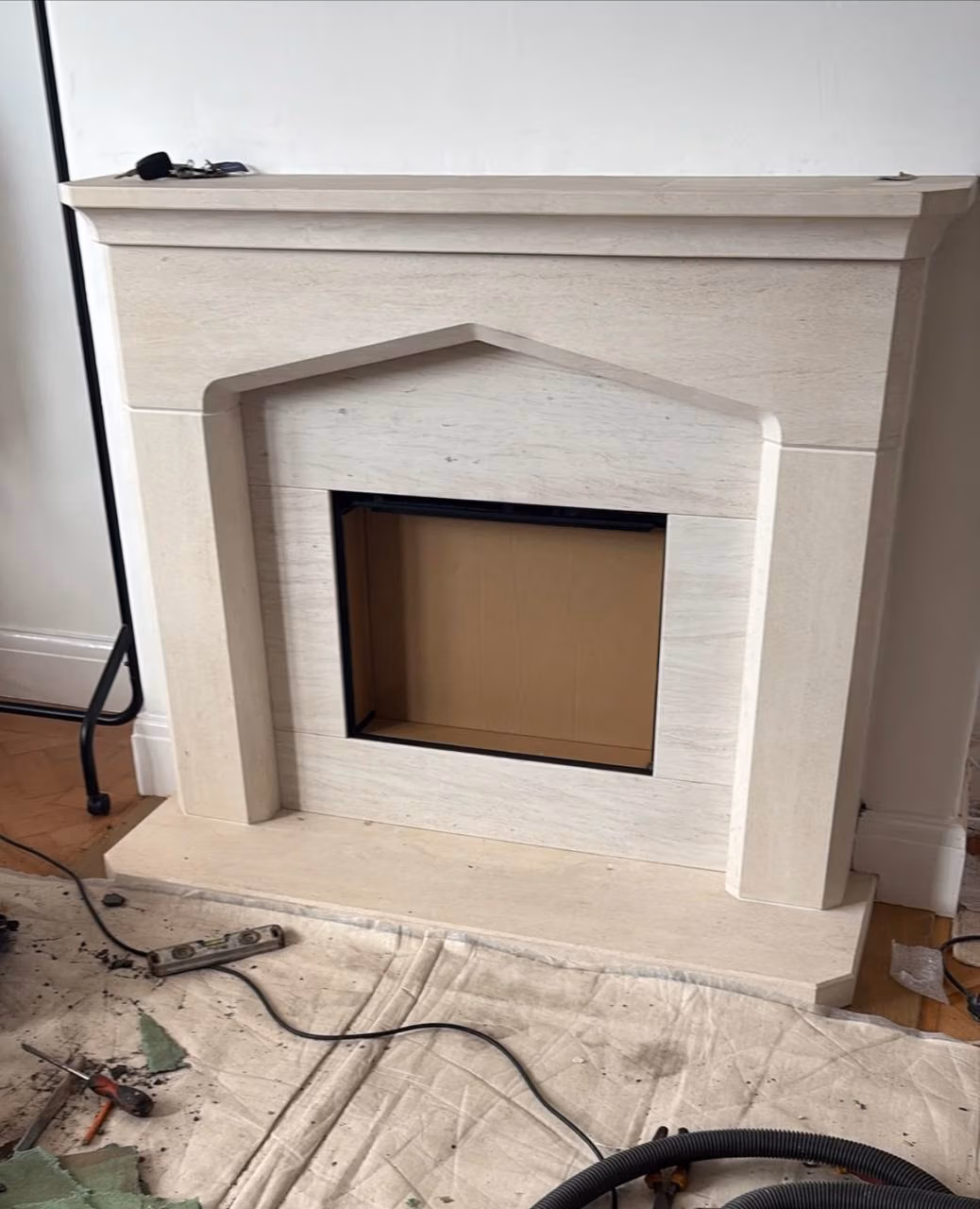 Light stone fireplace surround with unfinished fire opening during installation