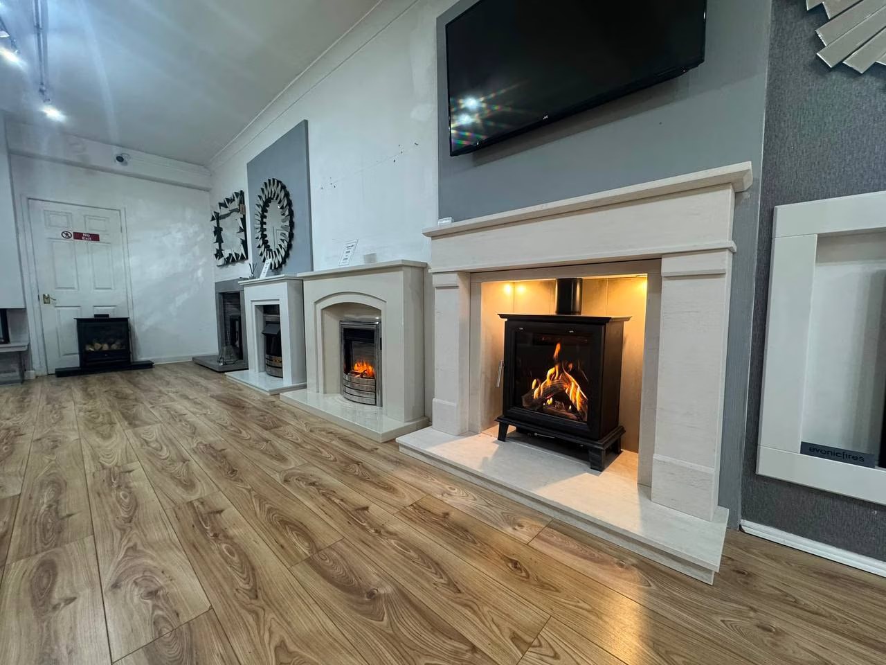 Lit log burner in a stone surround on display at the Heatwave Fireplaces showroom in Warrington