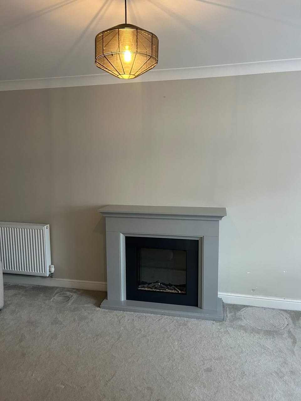 Before: grey painted fireplace surround with an electric fire, prior to the stove installation